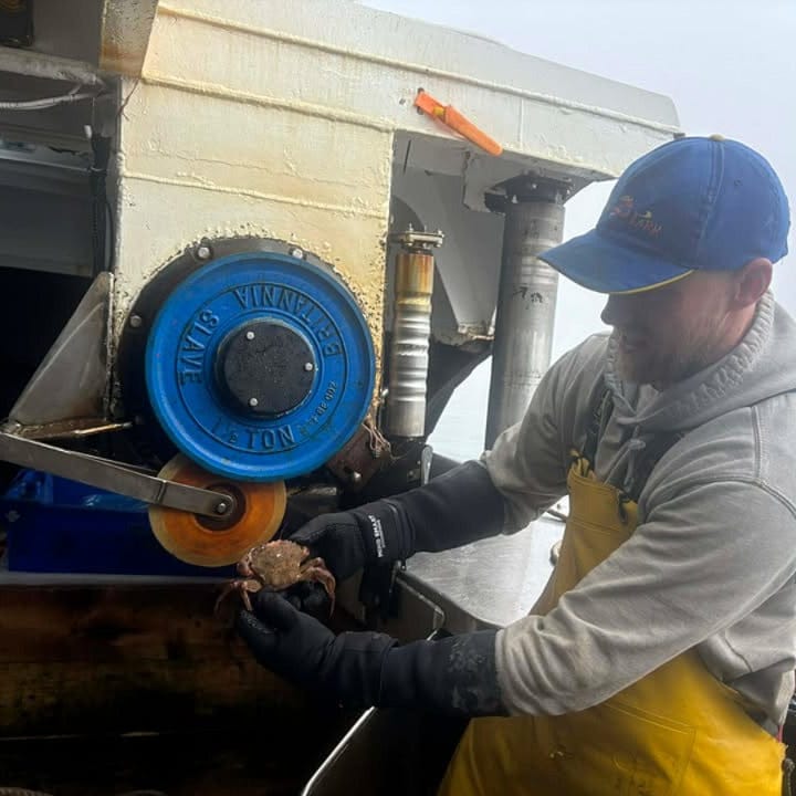 Fisherman operating a large mechanical pulley system on a boat